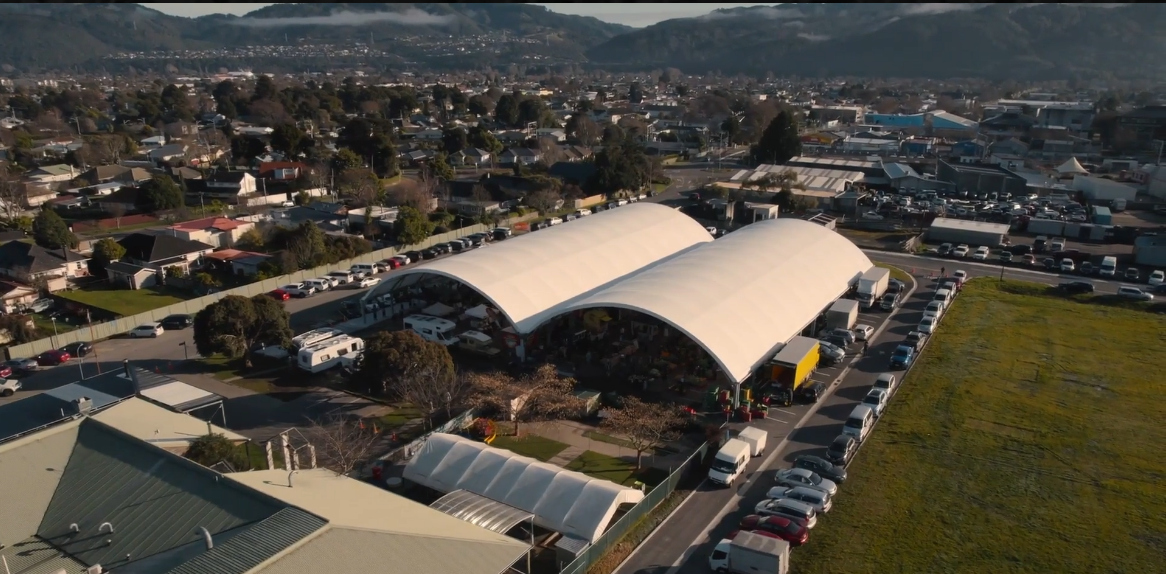 Aerial view of Brewtown Farmers Market in Upper Hutt, showcasing Sunday stalls, food trucks, and local crowds beneath twin white market tents.